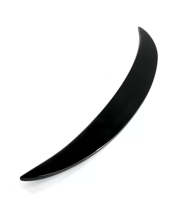 A sleek, curved black object, resembling a thin crescent, lies on a white surface. The object is glossy and tapers to a point at both ends.