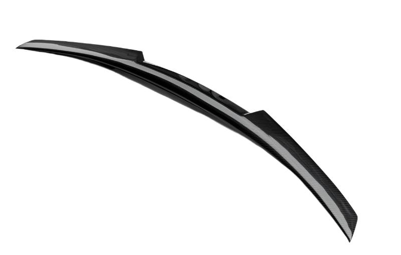 A sleek, curved black spoiler with a carbon fiber texture rests in isolation against a plain white background.
