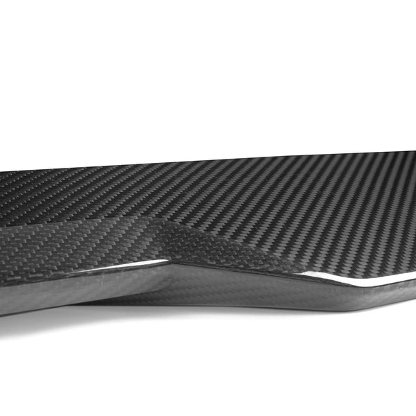 A sleek carbon fiber piece, displaying a glossy, woven texture, rests on a plain white background, emphasizing its modern design and intricate pattern.