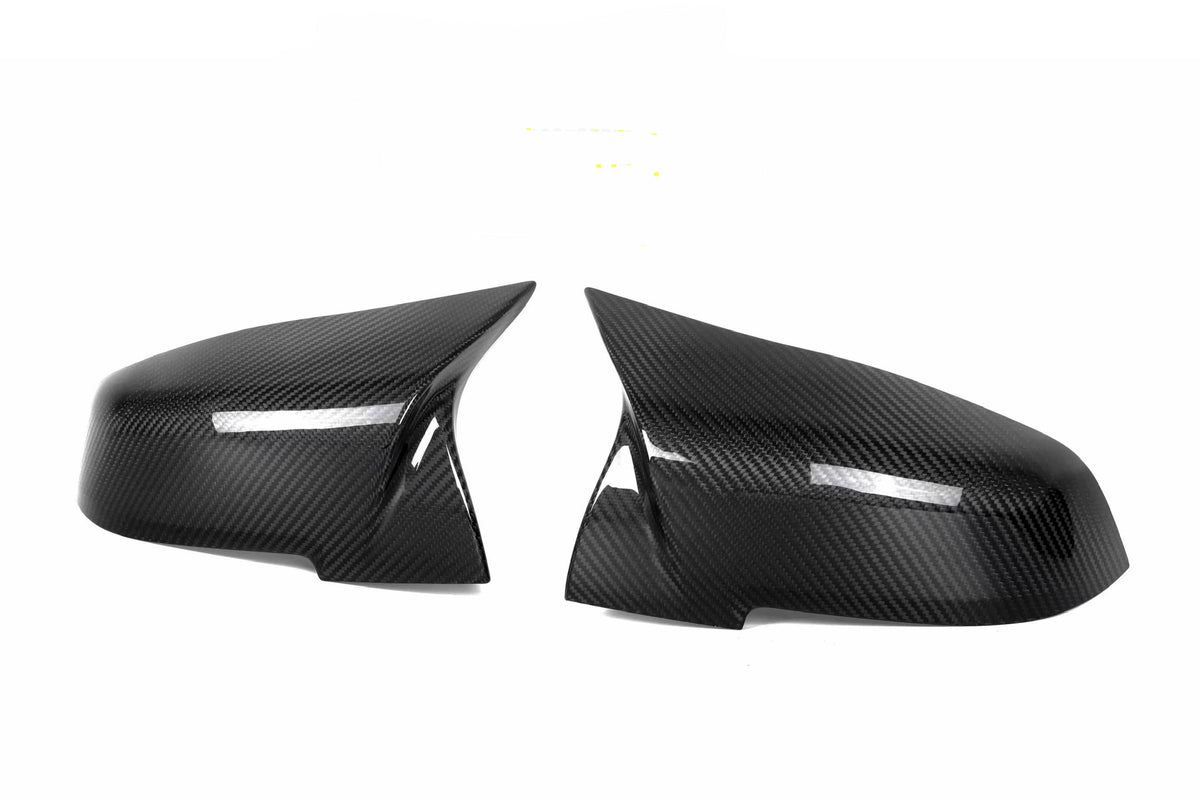 Two carbon fiber car mirror covers are positioned symmetrically against a white background, displaying a sleek, glossy finish with a visible weave pattern.