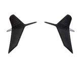 Two symmetrical, carbon fiber aerodynamic winglets are displayed, pointing slightly outward, set against a plain white background.