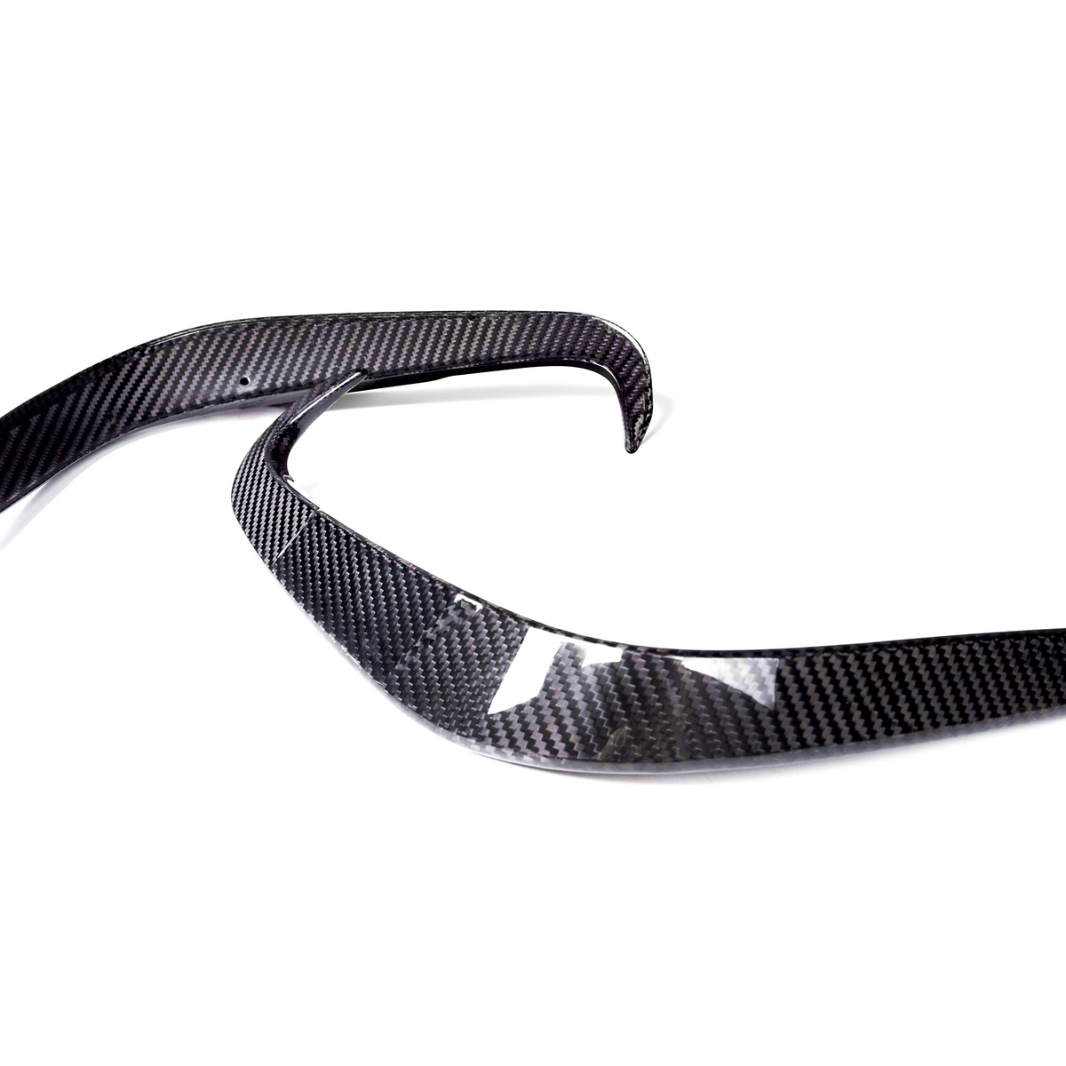 Two curved carbon fiber pieces are positioned parallel on a white background, likely automotive parts, showcasing sleek, aerodynamic lines and a glossy finish.