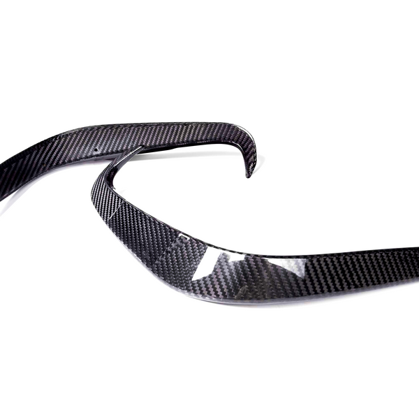 Two curved carbon fiber pieces are positioned parallel on a white background, likely automotive parts, showcasing sleek, aerodynamic lines and a glossy finish.