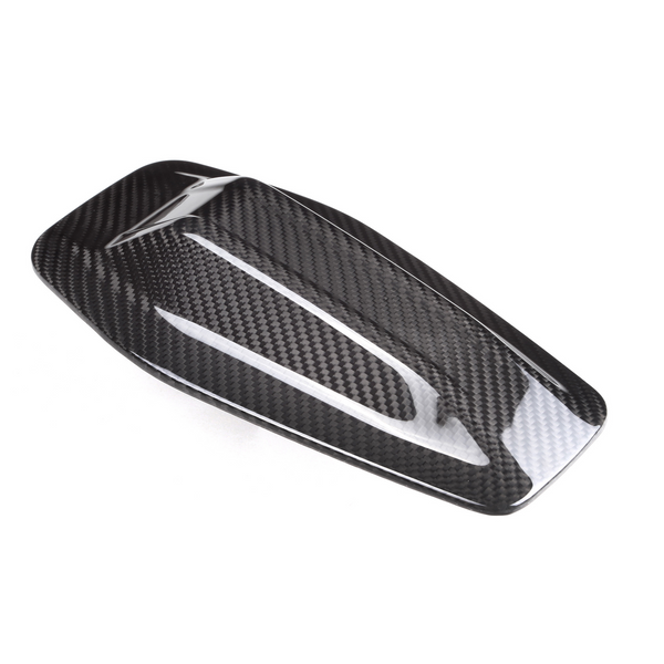 A sleek, carbon fiber car side mirror cover with a glossy finish, resting against a plain white background, highlighting its aerodynamic design and textured pattern.