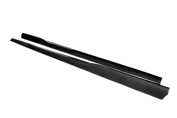 Two elongated, black carbon fiber car-side skirts lay parallel on a white surface, emphasizing their sleek, aerodynamic design.