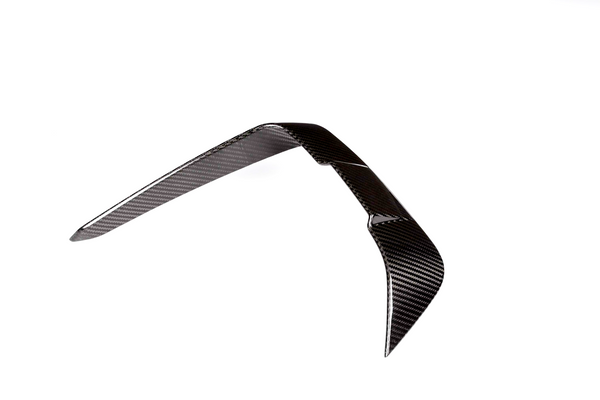 A shiny carbon fiber boomerang rests in a balanced, upright position against a plain white background, displaying a smooth, woven texture.