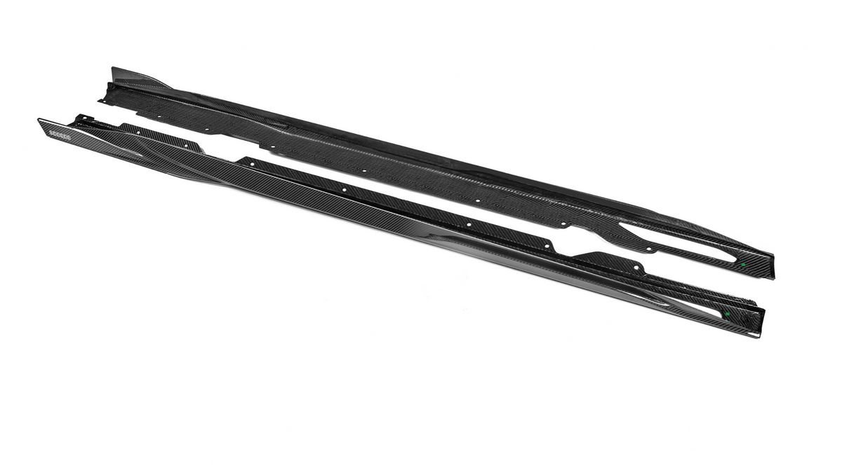 Carbon fiber car side skirts rest on a white surface. The upper skirt is slightly elevated, while the lower one is flat. The label reads "Spoon" in the corner.