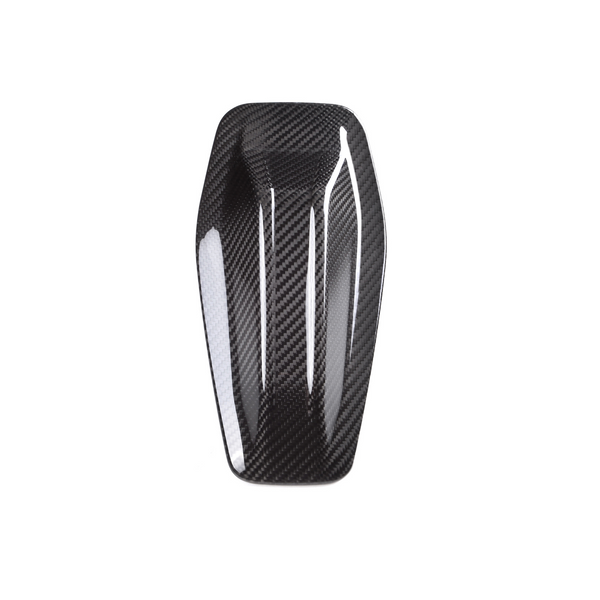 A sleek, elongated carbon fiber object resting against a plain white background. The object features a glossy, patterned surface with curved edges and subtle indentations.