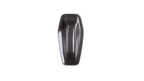 A sleek, elongated carbon fiber object resting against a plain white background. The object features a glossy, patterned surface with curved edges and subtle indentations.