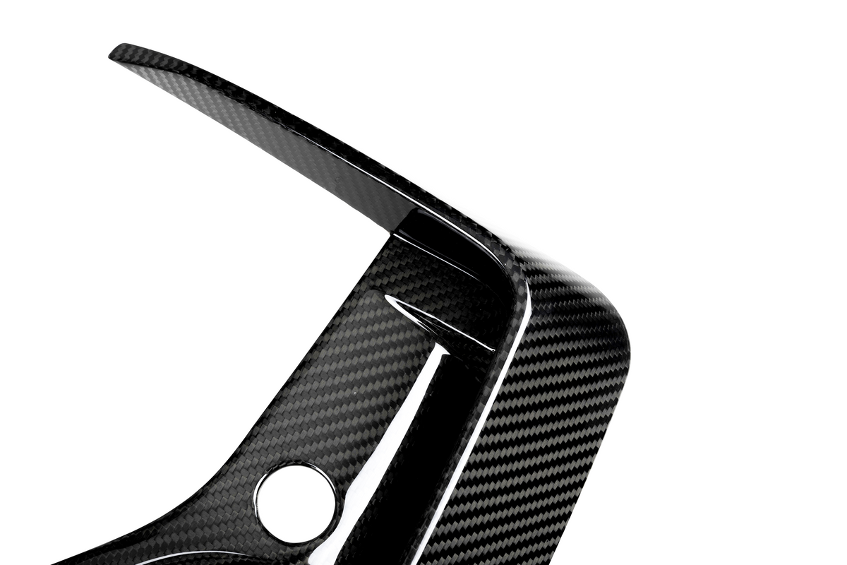 A carbon fiber car part features a curved, aerodynamic design with a circular hole, set against a plain white background.
