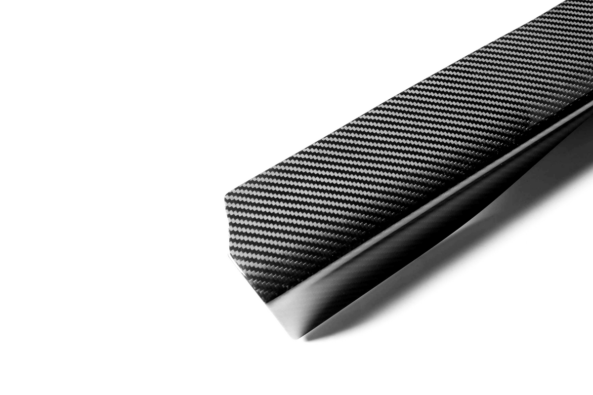 A carbon fiber bar with a glossy, woven texture rests on a plain white background, highlighting its sleek, modern design.