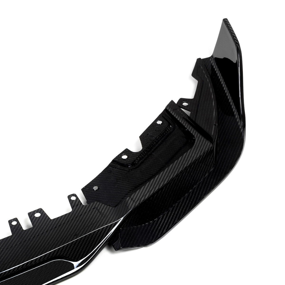 A glossy carbon fiber car accessory, likely a bumper, lies on a plain white background. The item features aerodynamic curves and multiple mounting points for attachment.