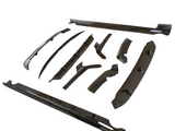 Car body kit components arranged on a white surface, including various sleek, black aerodynamic parts such as side skirts, spoilers, and diffusers, designed to enhance vehicle performance and appearance.