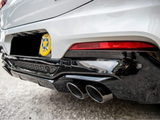 Car rear shows black triple exhaust pipes and red taillight, parked on asphalt. Yellow badge reads 