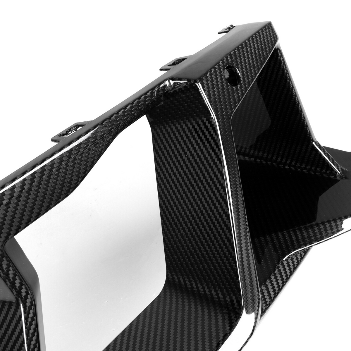 A sleek, black carbon fiber car part with geometric design, featuring sharp angles and contours, is placed against a plain white background.