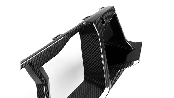 A sleek, black carbon fiber car part with geometric design, featuring sharp angles and contours, is placed against a plain white background.