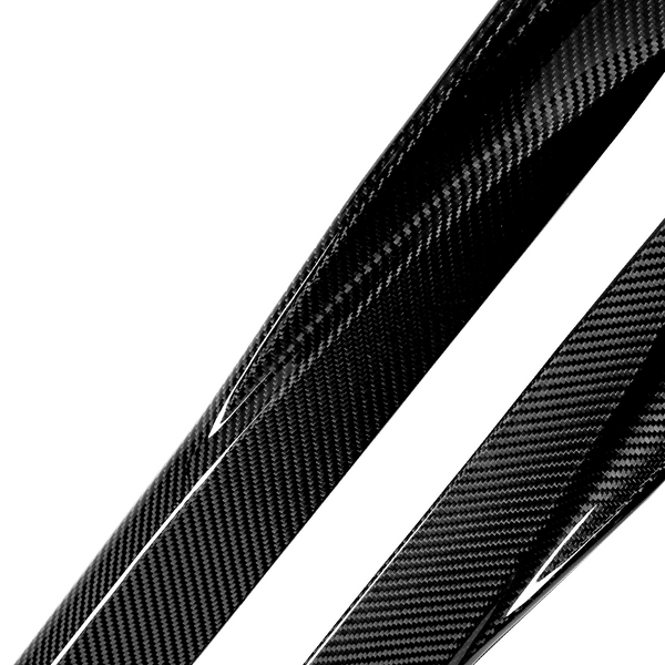 Glossy carbon fiber strips with a distinctive woven pattern lie diagonally on a white background, reflecting light and emphasizing their texture and sleek appearance.