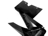 A carbon fiber automotive component with sleek, angular design lays on a plain white background, showcasing its lightweight and durable structure.