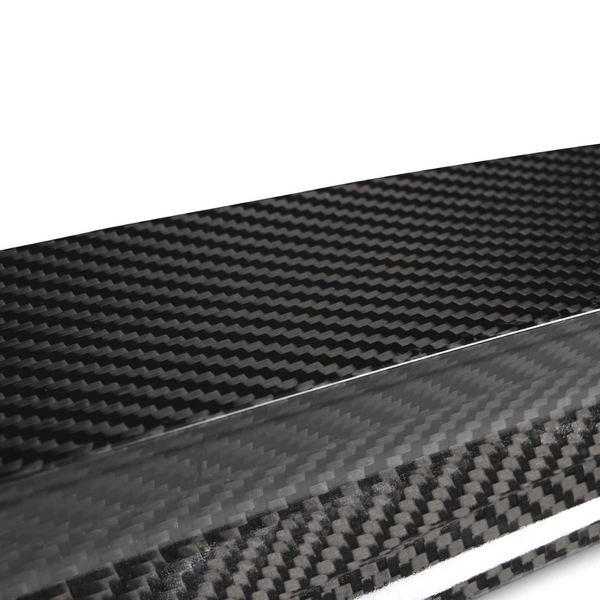 A close-up view of a glossy carbon fiber texture, displaying its distinctive woven pattern. The material appears sleek and polished, set against a plain, light background.