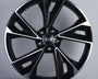 A black and silver alloy wheel with a geometric design and five dual spokes is displayed upright on a neutral background. The center features a logo with four interlocking rings.