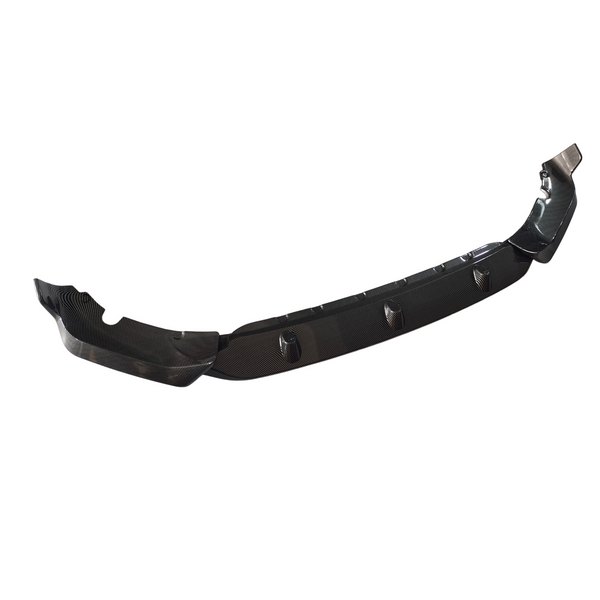 A carbon fiber car front splitter is shown, with a sleek contour and aerodynamic design. It has mounting holes and fins for airflow, set against a white background.