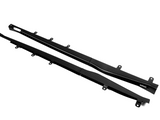 Two long, black carbon fiber car side skirts with mounting brackets lie on a white background. One piece features the text 