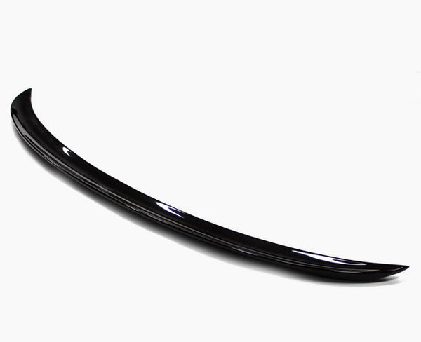 A sleek, black car spoiler with a smooth, curved design rests on a plain white background, highlighting its glossy finish and aerodynamic shape.