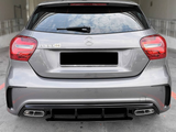 A gray Mercedes-Benz A180 car is parked, with visible rear lights and dual exhausts, in a concrete parking area. The badge 