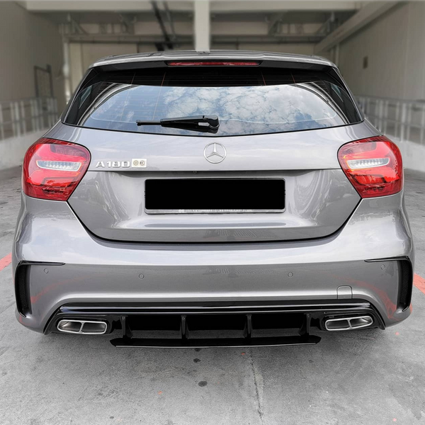 A gray Mercedes-Benz A180 car is parked, with visible rear lights and dual exhausts, in a concrete parking area. The badge "A 180" is on the left.