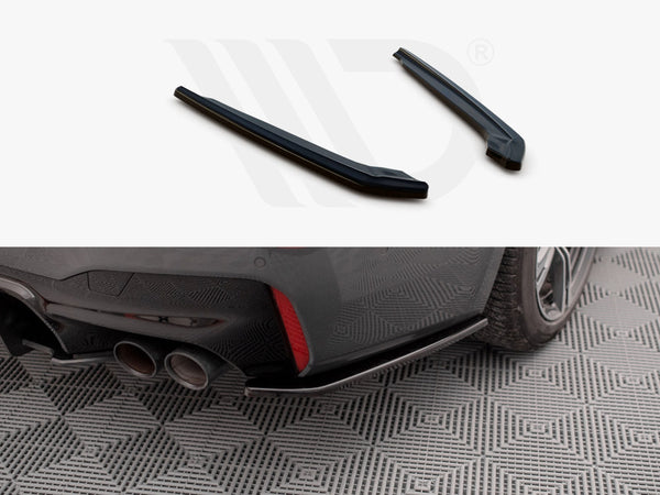 Two black car parts displayed above an installed piece on a car's rear bumper near dual exhaust pipes. The car is parked on a patterned surface.