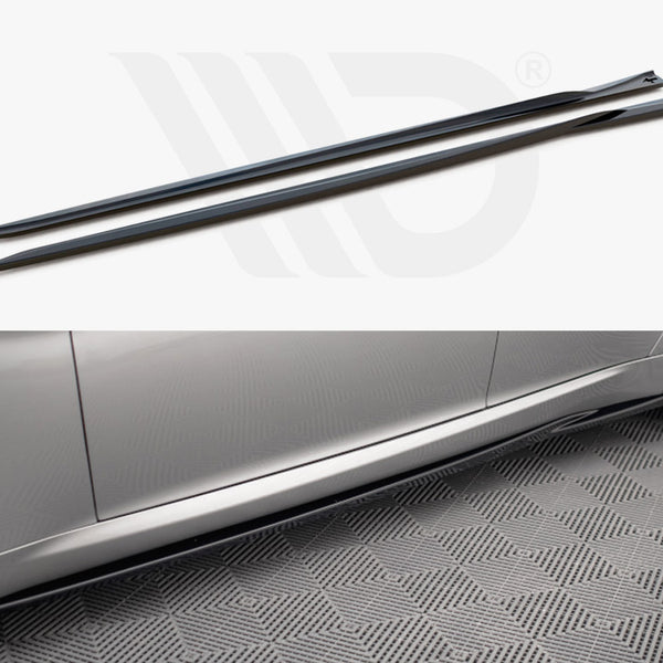 Two black side skirts lie parallel; below is a silver car with one skirt installed, resting on a textured gray floor.