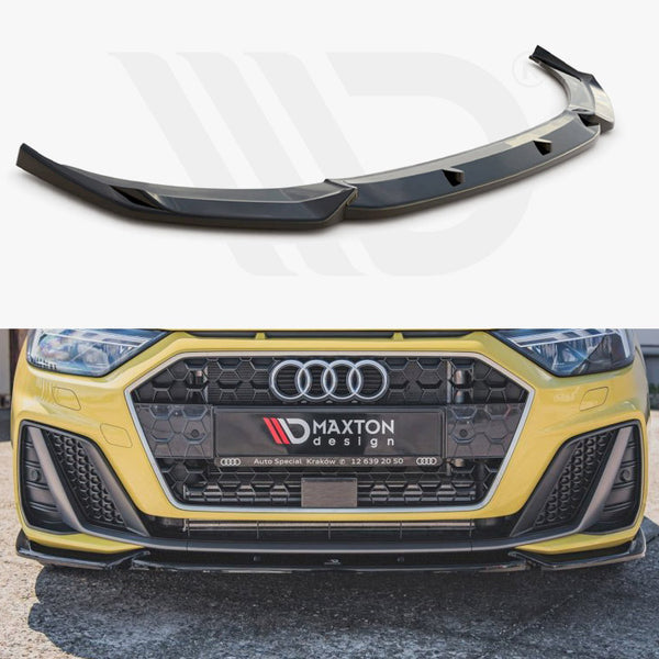 Car front splitter positioned above, installed on the yellow car’s front bumper below. Bumper displays the logo “Maxton Design” and contact details, set outdoors on a paved surface.