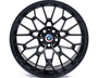 A black alloy wheel with a complex geometric spoke design features a BMW emblem at the center. It rests on a plain white background.