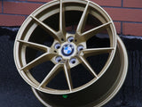 A gold BMW car wheel lies against a brick wall. The wheel is detailed and has a logo at its center. The design is sleek and modern.