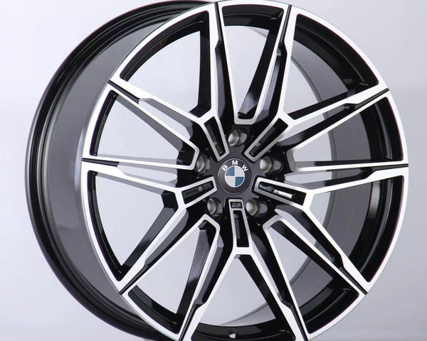 A black and silver multi-spoke alloy car wheel with a BMW logo is positioned upright against a plain white background, showcasing a sleek, modern design.