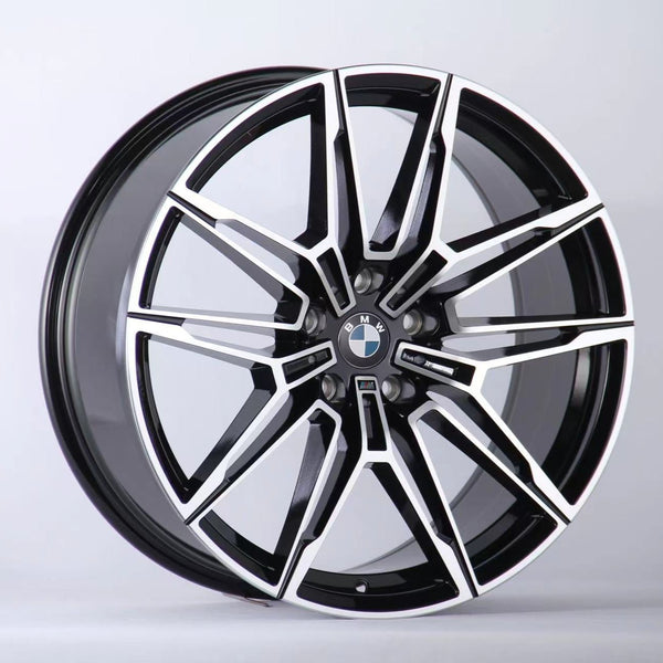 A black and silver multi-spoke alloy car wheel with a BMW logo is positioned upright against a plain white background, showcasing a sleek, modern design.