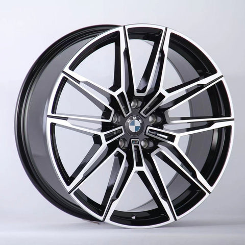 A black and silver multi-spoke alloy car wheel with a BMW logo is positioned upright against a plain white background, showcasing a sleek, modern design.