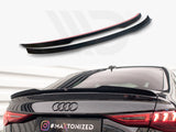 Two black car spoilers sit on a plain background above a black Audi with one spoiler installed on the trunk. License plate reads: 