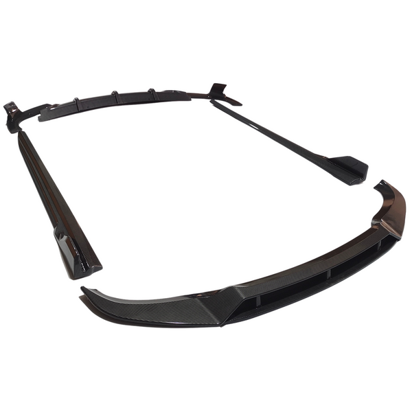Several carbon fiber car body kit pieces are arranged on a white surface, including a front splitter, side skirts, and a rear diffuser, emphasizing their sleek, aerodynamic design.