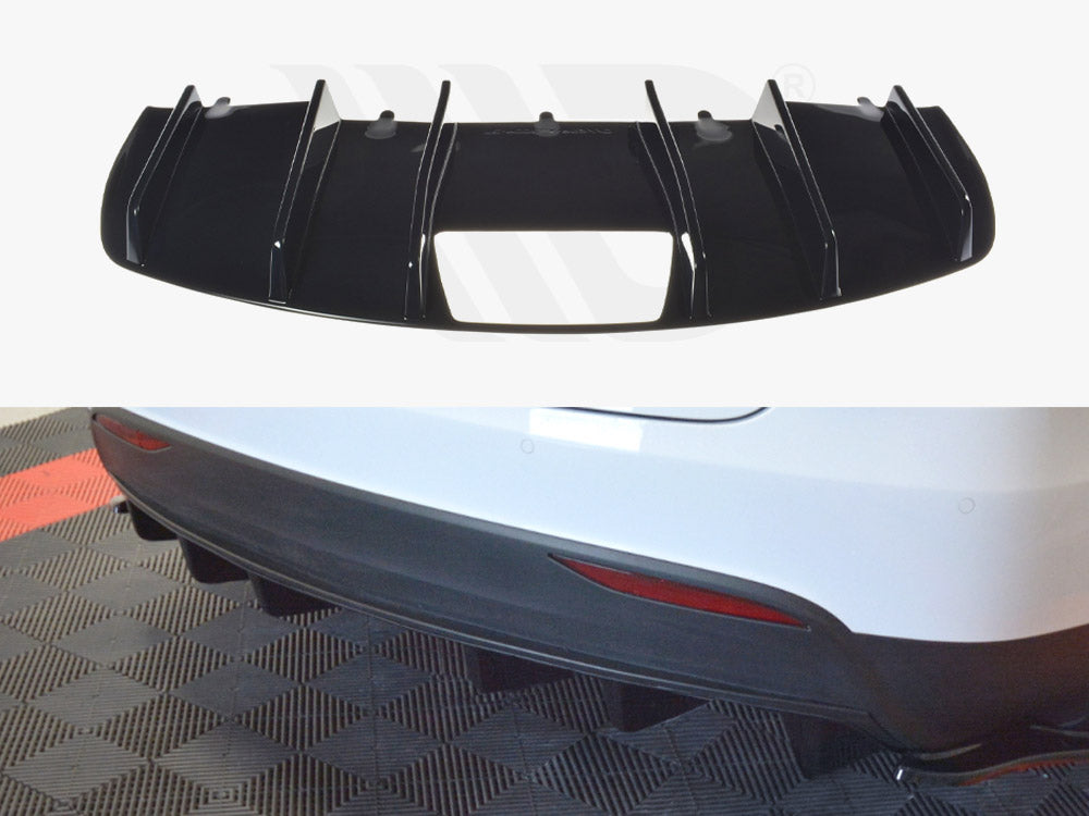 A black vehicular rear diffuser with vertical fins is shown, designed for aerodynamic purposes. It is intended to be installed on a white car's rear bumper, seen parked on a textured floor.