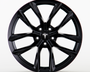 A black wheel rim featuring a sleek, multi-spoke design with the Tesla logo visible at the center, placed against a plain white background.