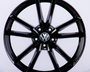 A black alloy car wheel is displayed with a five-spoke design, featuring the Volkswagen logo in the center, set against a plain white background.