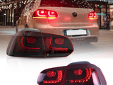Car with glowing red taillights idling in a brightly lit urban setting; focus on a close-up view of the taillight design below, featuring multiple LED segments.