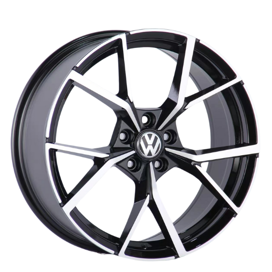 A black and silver alloy wheel with a geometric pattern, displaying the Volkswagen logo in the center, is positioned against a plain white background.