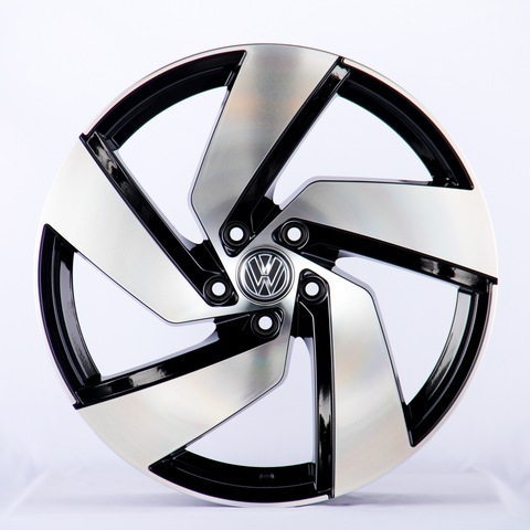 A metallic car wheel with a five-spoke design featuring a central logo; it rests against a plain white background.