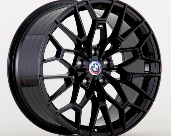 A black alloy wheel showcases a geometric, multi-spoke design, prominently featuring a BMW logo at its center against a plain, light gray background.
