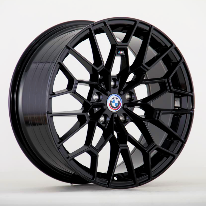 A black alloy wheel showcases a geometric, multi-spoke design, prominently featuring a BMW logo at its center against a plain, light gray background.
