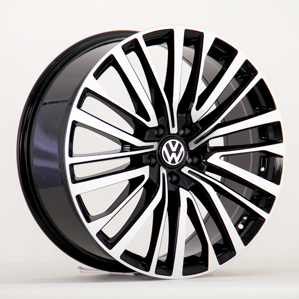 A black and silver alloy car wheel features a sleek, multi-spoke design with a Volkswagen logo at the center, positioned on a plain white background.