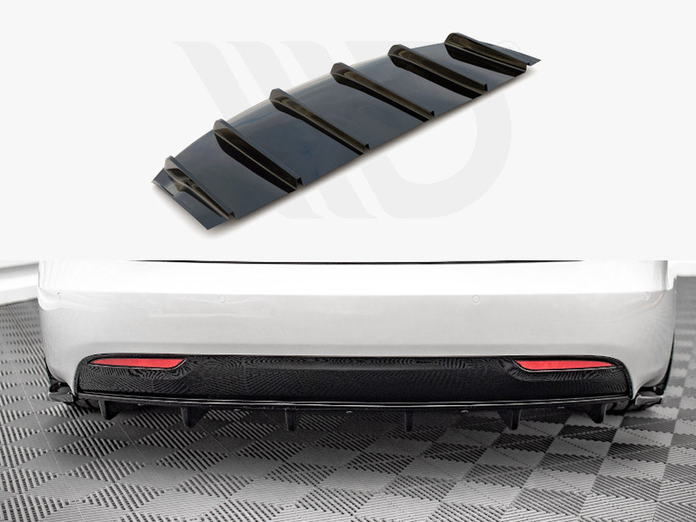 A black car diffuser, featuring multiple fins, lies separately above a white car's rear bumper. The car is on a checkered floor, with visible red reflectors.