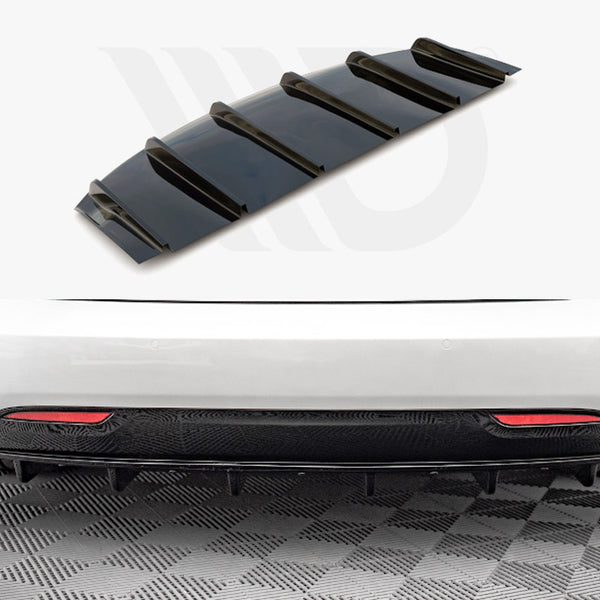 A black car diffuser, featuring multiple fins, lies separately above a white car's rear bumper. The car is on a checkered floor, with visible red reflectors.